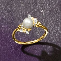 a pearl and diamond ring on a purple surface