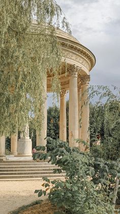 a gazebo with columns and trees surrounding it