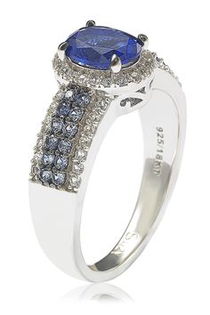 A blue sapphire halo ring features a sparkling pave encrusted band for luxe glamour. Sterling silver oval cut sapphire halo and pave sapphire embellished band ring with hidden brown diamond accent. Approx. 10mm L x 5mm W ring face. ImportedPlease note: Diamond weight may not be exact. Oval Sapphire Ring With Pave Setting For Anniversary, Oval Blue Diamond Ring With Pave Setting, Sapphire Ring With Pave Setting For Anniversary, Anniversary Tanzanite Halo Ring, Sapphire Halo Ring With Diamond Accents For Anniversary, Blue Sapphire Halo Ring, Sapphire Anniversary Ring, Sapphire Halo Ring, Sapphire Anniversary