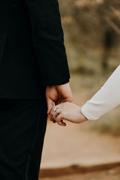 a man and woman holding hands while standing next to each other