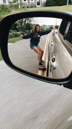 a woman skateboarding in the side view mirror of a car