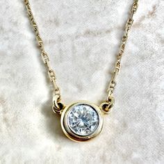 A spectacular vintage 14 karat yellow and white gold solitaire pendant necklace featuring a 5.25 mm natural round diamond weighing approximately 0.60 carat. It is G-H in color and VS2 in clarity. The necklace is 15 inches long. The bezel is 7.50 mm in diameter. The chain is 1.25 mm thick and equipped with a safety snap tab. Weighs 3.42 grams. Stamped 14K. Birthstone: April. Condition: Very good. Light scratches and wear throughout metal. - 14 day return policy, no questions asked. - Free insured Vintage Yellow Gold Diamond Necklace, Timeless Yellow Gold Solitaire Necklace With Round Stone, Classic Yellow Gold Solitaire Diamond Necklace, Classic Round Stone Diamond Necklace, Classic Diamond Necklace With Round Single Diamond, Classic Round Cut Diamond Necklace With Bezel Setting, Classic Diamond Necklace With Single Round Stone, Classic 14k Yellow Gold Solitaire Necklace, Classic Yellow Gold Diamond Necklace With Round Stone