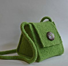 a green felt purse with a button on the front and shoulder strap, sitting on a white surface