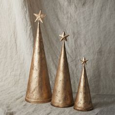 three small gold christmas trees with stars on top, one in the shape of a cone