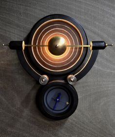 a black clock with gold accents on it's face and two pendulums in the middle