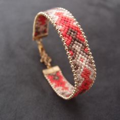 a close up of a bracelet on a black surface with red and white beads around it