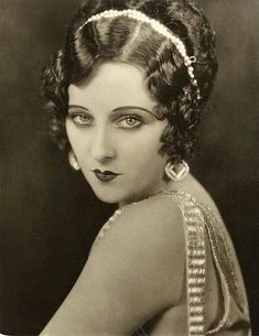 an old black and white photo of a woman with braids in her hair, wearing a dress