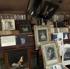 many paintings and pictures are on display in a room with bookshelves full of books