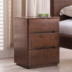 a wooden night stand with two drawers on top of it next to a white bed