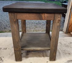 a small wooden table sitting on top of a cement floor next to a gravel road