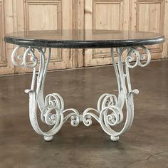 an ornate table with black marble top in front of wooden paneled walls and doors