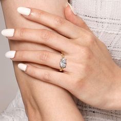 a woman's hand with white manicured nails and a ring on her finger