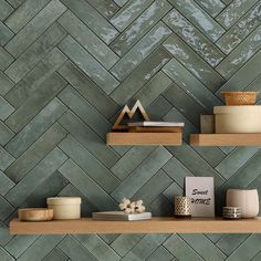 two shelves with vases, books and other items on them in front of a green tiled wall