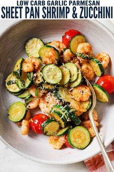 a white bowl filled with shrimp, zucchini and tomatoes next to a fork