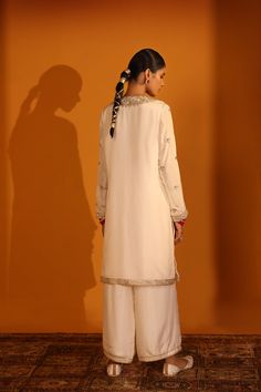 IVORY EMBELLISHED KURTA SET WITH PANTS AND DUPATTAThis kurta set is a graceful embodiment of elegance, with a delicate ivory tone that exudes charm. It features intricate naqshi, zardozi, and gota embroidery, accented with hand-stitched sequins. The loose-fitting bottoms paired with the kurta create an enigmatic aura, further enhanced by the ivory- hued organza dupatta. Fabrics : HABUTAI SILK ORGANZA Color : IVORY Item: KURTA SET / KURTA PANT DUPATTA Elegant Cream Palazzo Set For Reception, Elegant Off-white Festive Sets, Elegant Semi-stitched Sherwani In Straight Kurta Style, Elegant Off White Embroidered Sets, Elegant Semi-stitched Sharara With Naqshi Details, Elegant Semi-stitched Embroidered Sharara, Elegant Semi-stitched Silk Sherwani, Elegant Off White Sets With Intricate Embroidery, Elegant Off-white Sets With Intricate Embroidery