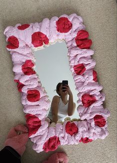 a person taking a selfie in front of a pink and red flowered mirror