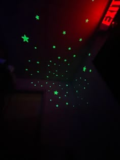 a room with green stars on the wall and black walls, all lit up by red light