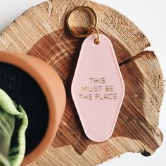 a keychain that says, this must be the place next to a potted plant