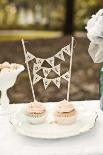 two cupcakes sitting on top of a plate next to a vase with flowers