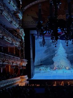 the stage is lit up with chandeliers and christmas decorations on it, as people watch