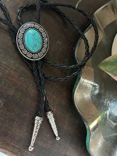 This awesome bolo tie has a southwestern design and genuine turquoise stone centerpiece. It is handmade in our shop.  The cord is genuine black leather. Our bolos pair nicely with many of our belt buckles! They make wonderful gifts.    The western bolo tie rope length is 39'' ; charm agate stone pendant size is 1 1 1/4'' x 1 1/2'' Western Jewelry With Adjustable Length For Rodeo, Western Jewelry With Adjustable Length For Western-themed Events, Western Style Adjustable Jewelry For Western-themed Events, Handmade Bohemian Bolo Tie For Rodeo, Bohemian Bolo Ties For Western-themed Events, Black Southwestern Jewelry For Rodeo, Southwestern Black Jewelry For Rodeo, Vintage Black Jewelry For Western-themed Events, Adjustable Cord Jewelry For Western-themed Events