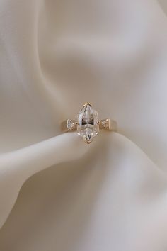 an engagement ring on top of a white cloth