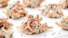 cookies with white frosting and sprinkles are arranged on a baking sheet