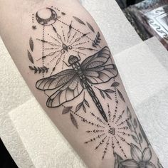 a black and white dragonfly tattoo on the arm