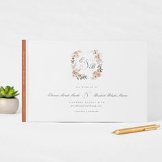 a wedding card with the letter s on it next to a pen and succulent plant