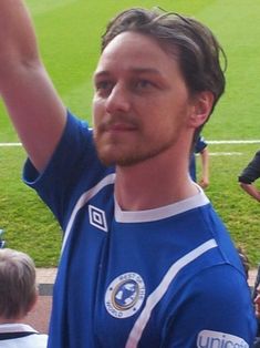 a man in a blue shirt is holding his hand up to the sky with other people around him