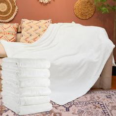 a pile of white blankets sitting on top of a bed next to pillows and rugs