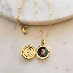 The Locket Necklace with Photo is a beautiful and sentimental piece of jewelry that is perfect for keeping your loved ones close to your heart. This personalized necklace features a round locket pendant that opens up to reveal a space for your favorite photo. The locket is 18K gold plated, which gives it a luxurious and timeless look. The necklace itself is also 18K gold plated and adjustable to fit any neck size comfortably. It has a secure clasp that ensures the locket stays in place, so you c Dainty Locket Jewelry For Mother's Day, Memorial Locket Jewelry For Mother's Day, Mother's Day Memorial Locket Jewelry, Dainty Locket Charm Necklace For Anniversary, Locket Charm Necklace With Round Pendant, Anniversary Locket Charm Necklace With Round Pendant, Personalized Yellow Gold Locket Necklace For Mother's Day, Round Birthstone Locket Necklace For Anniversary, Gold Pendant Locket Necklace With Birthstone