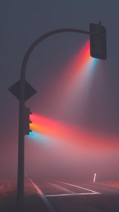 a traffic light on a foggy day with the sun shining brightly in the background