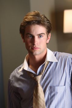 a young man wearing a shirt and tie in a room with a lamp on the wall