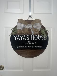 a sign that says yaya's house hanging on a door with a bow