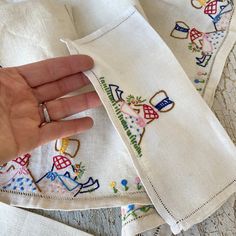 someone is holding their wedding ring on top of two handkerchiefs with hand embroidered designs