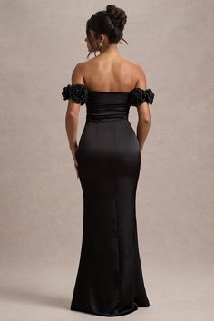 the back of a woman in a black evening gown, looking down at her shoulder