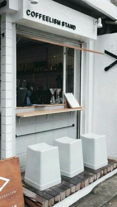 the outside of a coffee shop with three white stools in front of it and a sign that says coffeelish stand