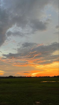 the sun is setting over an open field