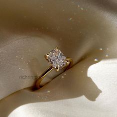 a diamond ring sitting on top of a white satin material with the light shining through it