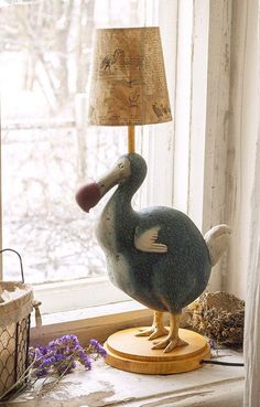 a bird figurine sitting on top of a window sill next to a lamp