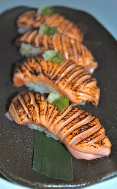 four pieces of sushi on a black plate