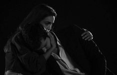 black and white photograph of a woman sitting on a chair with her hands over her face