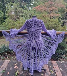 a purple crocheted shawl draped over a wooden deck