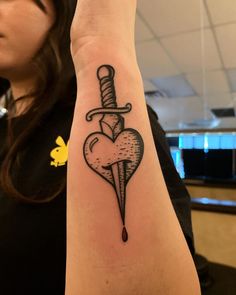 a woman with a tattoo on her arm holding up a knife and heart shaped dagger