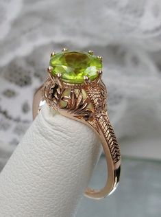 "Natural Peridot Ring Description Elizabeth Design#158 MADE TO ORDER Here we have a Victorian/Edwardian reproduction ring in sterling silver with rose gold overlay (rose gold \"embraced\") filigree with a natural peridot gemstone. This solitaire full cut round cut amethyst is 8mm in diameter. This ring also sits 8mm off the finger. The inside of the band is marked 925 for sterling. Notice the beautiful leaf design of the silver and gold filigree setting and etched band. This is a lovely renditio Green Wedding Rings With Accent Stones, Art Deco Green Wedding Rings, Antique May Birthstone Rings For Wedding, Antique May Birthstone Wedding Rings, Green Peridot Jewelry For Wedding, Wedding Ring With Hallmarked Peridot, Wedding Jewelry With Prong Setting And Peridot, Wedding Jewelry With Peridot In Prong Setting, Wedding Jewelry With Prong Set Peridot