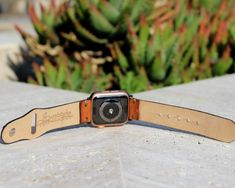 an apple watch sitting on top of a cement surface next to a planter with succulents in the background