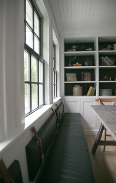 a long bench sitting in front of a window next to a book shelf filled with books