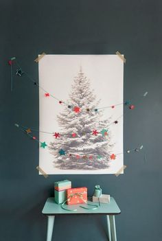 a small table with presents on it and a christmas tree hanging from the wall above