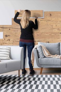 a woman standing next to a couch in front of a wall with wood planks